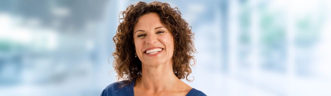 Dentist Sacramento CA Woman Smiling In Front Of Blue Background